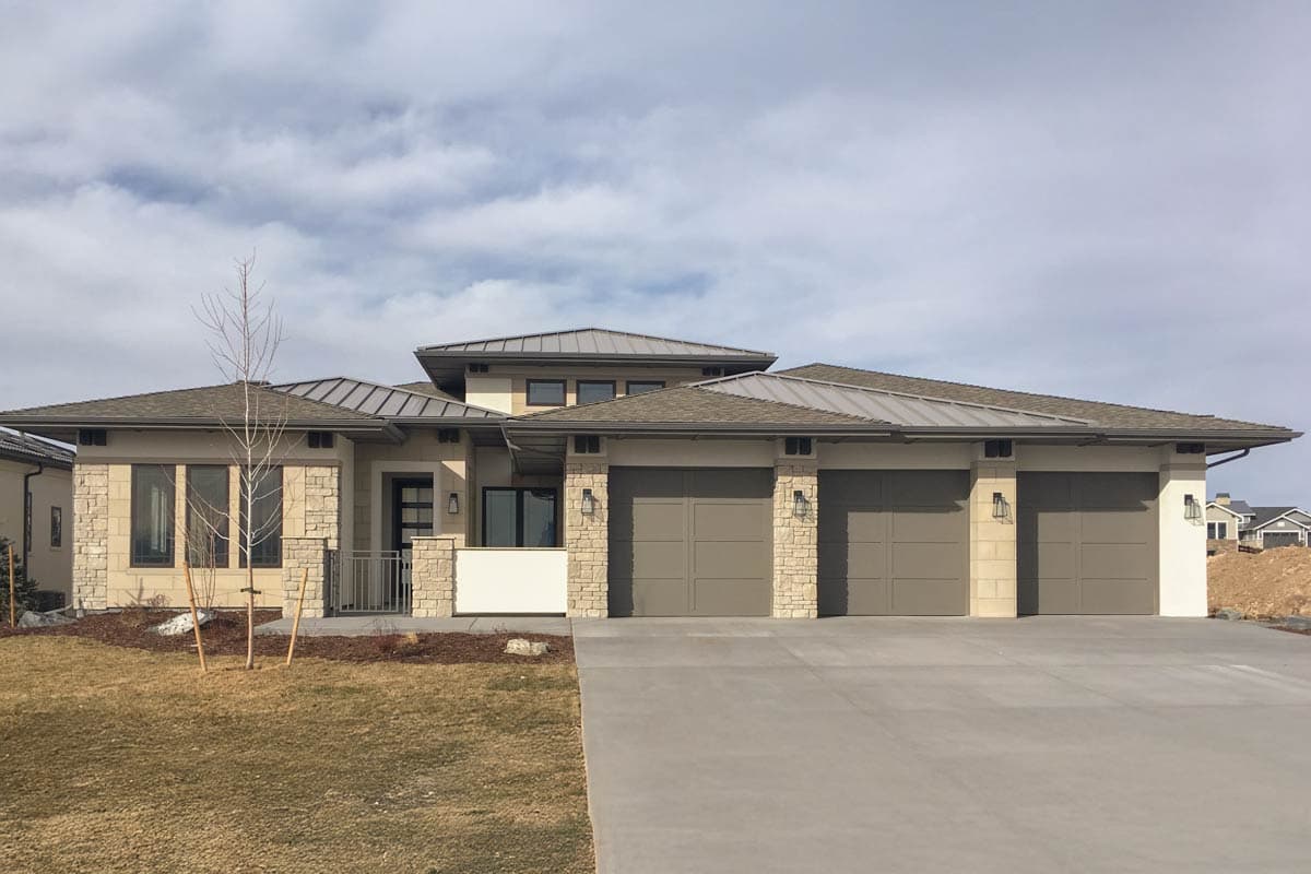 Modern house plan exterior with stone accents, low-pitched rooflines, and a three-car garage.
