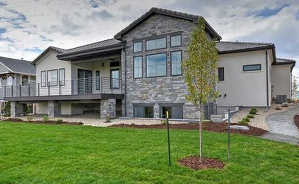 Modern house plan exterior with stone facade, elevated deck, and multiple gables.