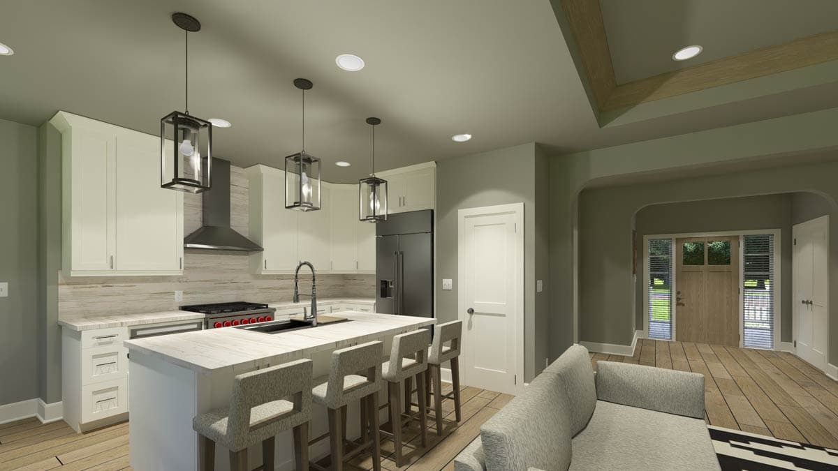 A modern kitchen with a large island and bar seating, sleek black appliances, and pendant lights. A doorway leads to an entryway with a wooden door.
