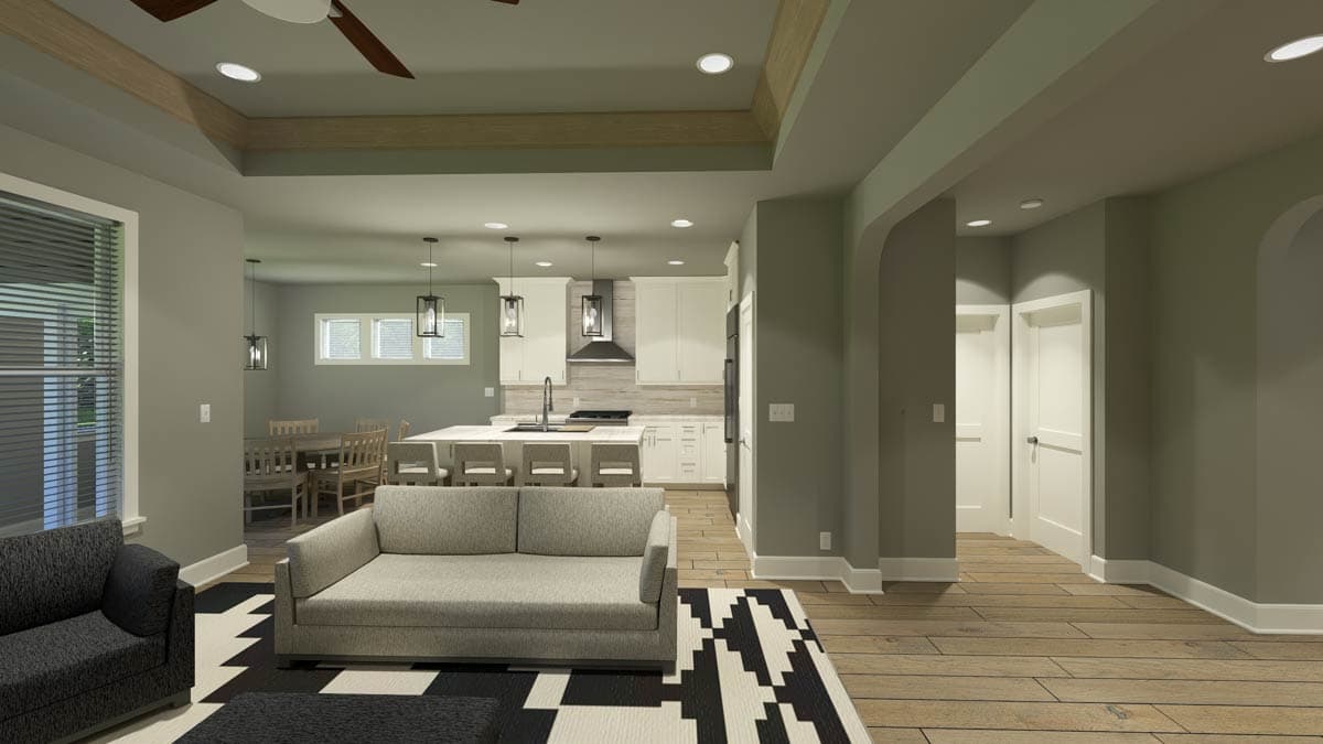 Spacious, modern living room with an open kitchen featuring a large island. A sofa sits atop a geometric rug in front of the kitchen.