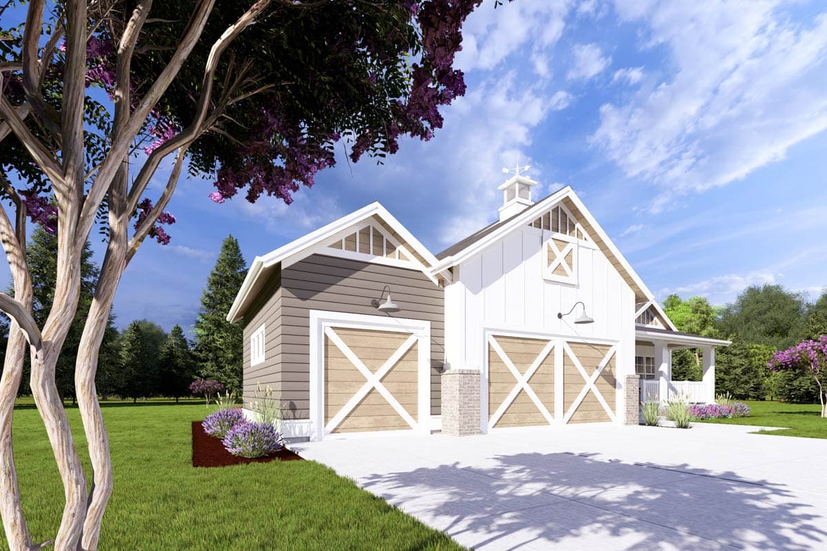 A two-bay garage with white and gray siding under a blue sky. Large tree in the foreground with purple flowers, green lawn and surrounding foliage.