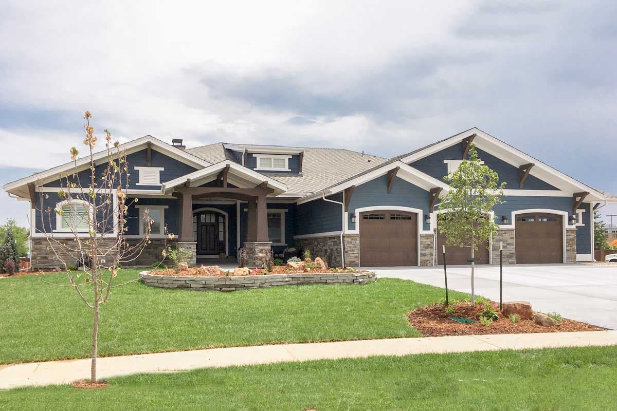 Craftsman house plan exterior. Features include a covered entry porch, multiple gables, and a three-car garage. Stone veneer accents the facade.