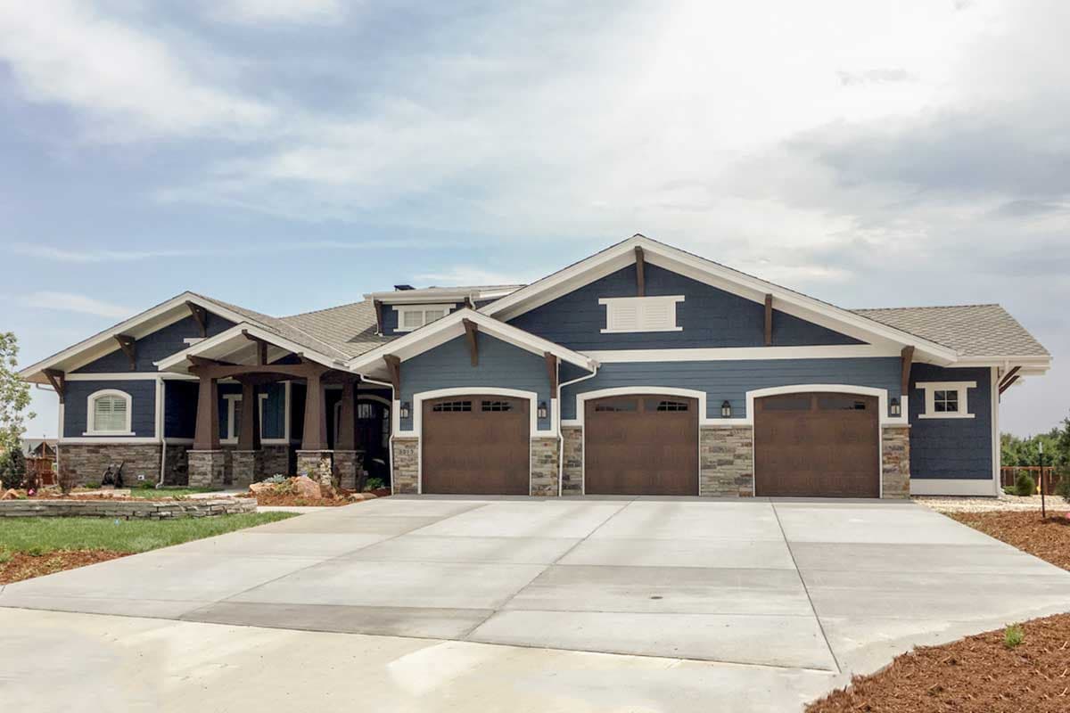 Craftsman style house plan exterior with a wide three-car garage, prominent gables, stone accents, and a covered entry.