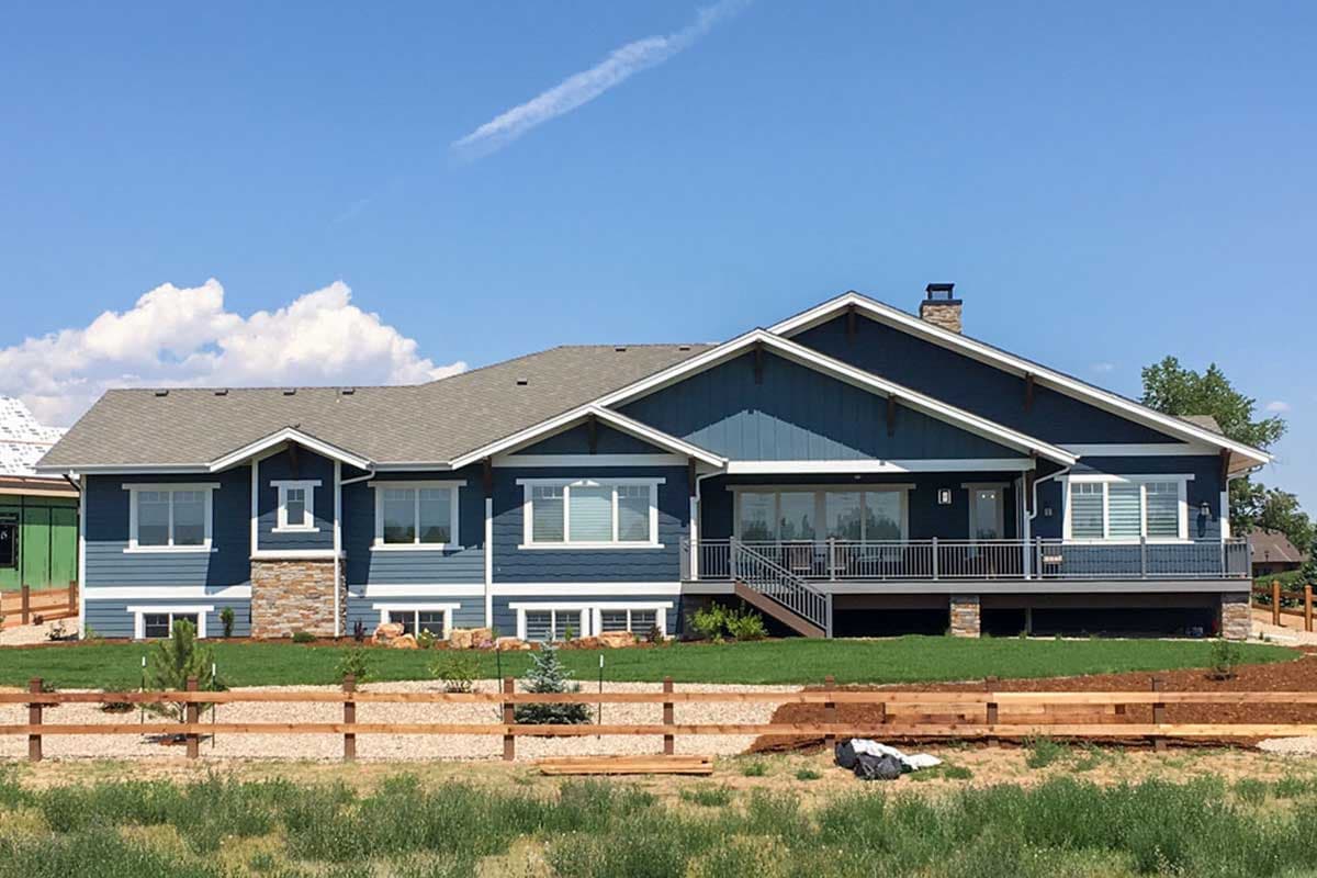 Craftsman style ranch house plan exterior with blue siding, stone accents, prominent gables, and a large deck.