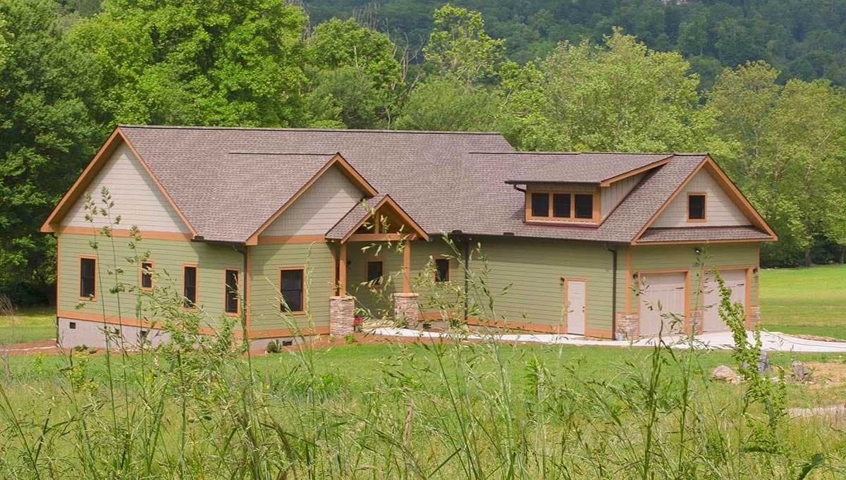 House plan exterior: Green, 1.5-story home with gabled dormers, stone-accented porch columns, and a three-car side-entry garage.