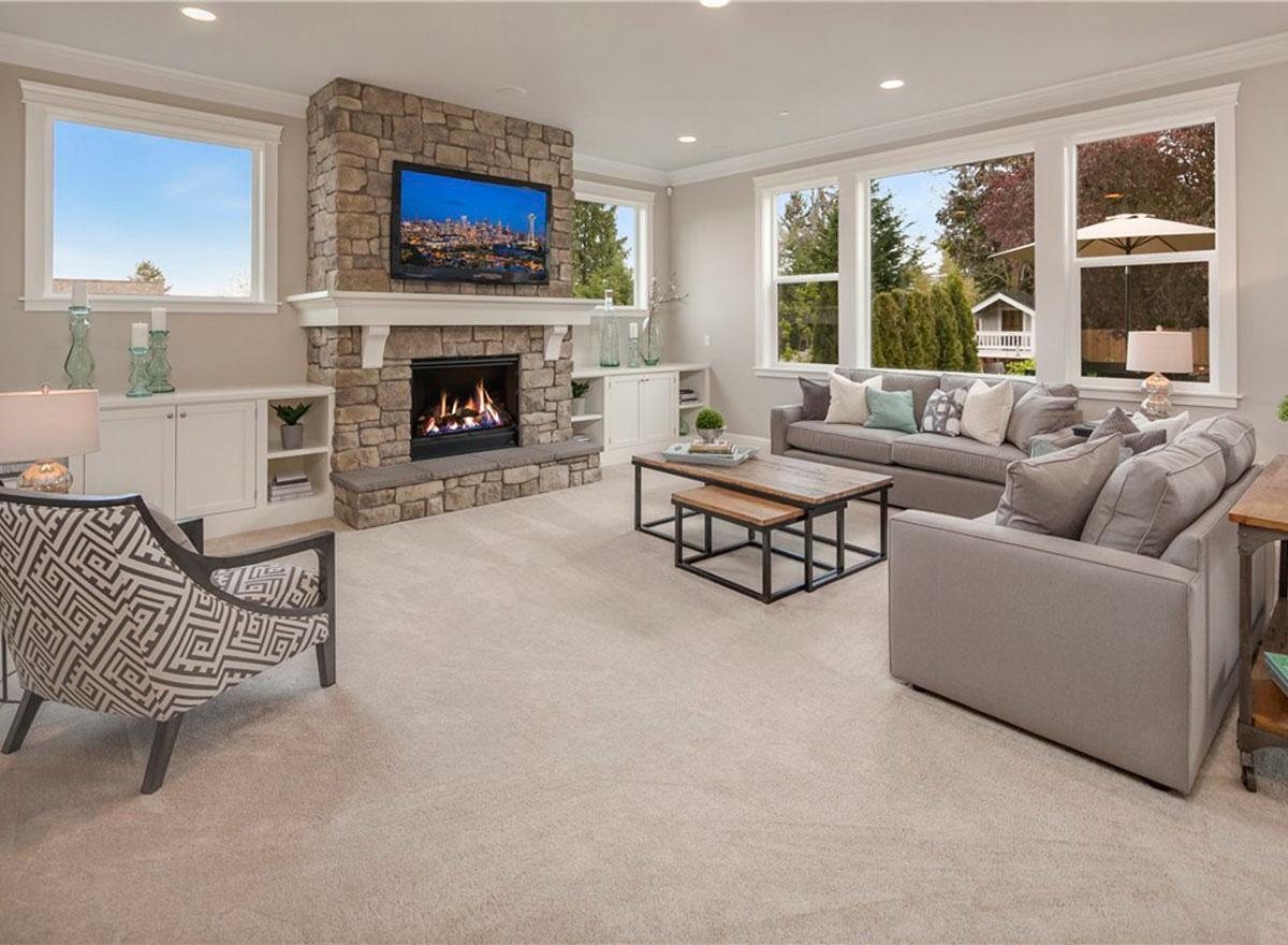 Living room with stone fireplace, built-in shelving, large windows, and sofas.