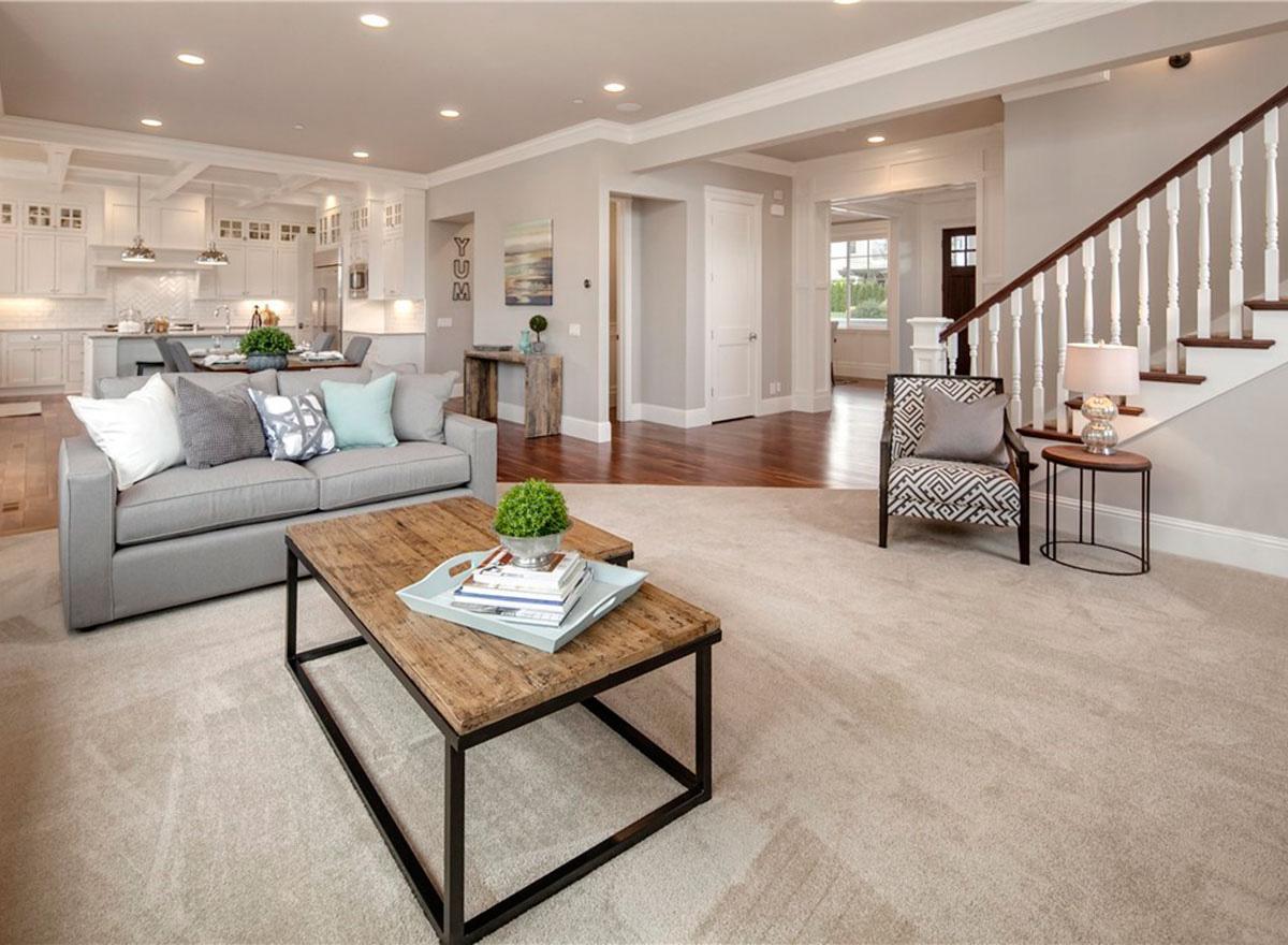 Great room and kitchen with island, coffered ceiling, fireplace, and staircase. Open layout.