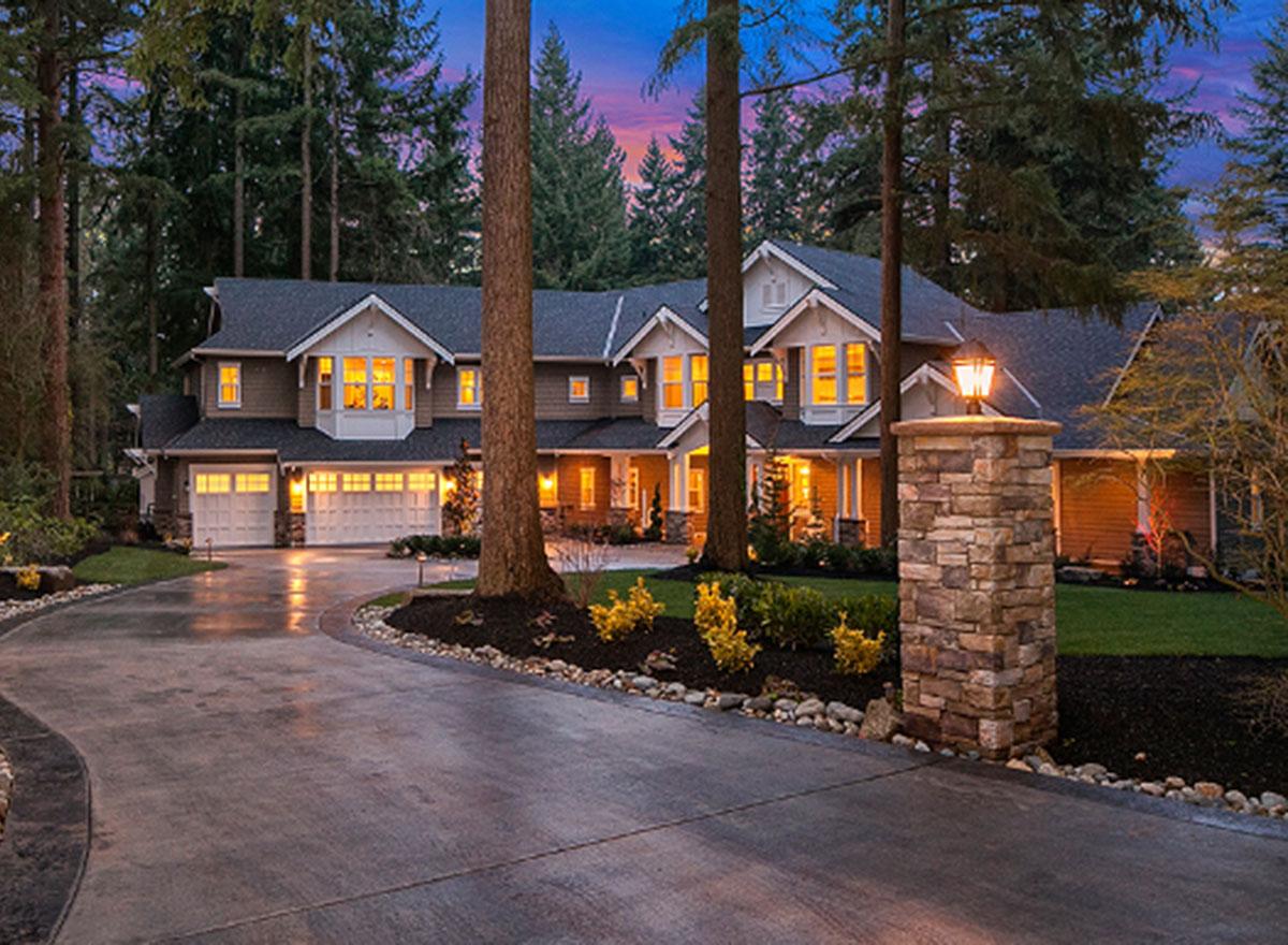 House plan exterior of a multi-story home with a wide driveway, three-car garage, multiple gables, and a stone pillar with a lantern.