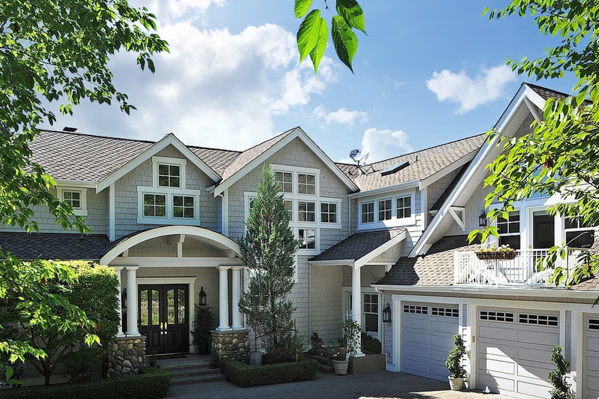 House plan exterior of a multi-story home with arched entryway, stone accents, multiple gables, and a three-car garage.