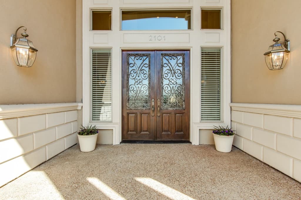 House plan exterior: Double wooden doors with decorative glass, flanked by tall windows and wall lanterns.