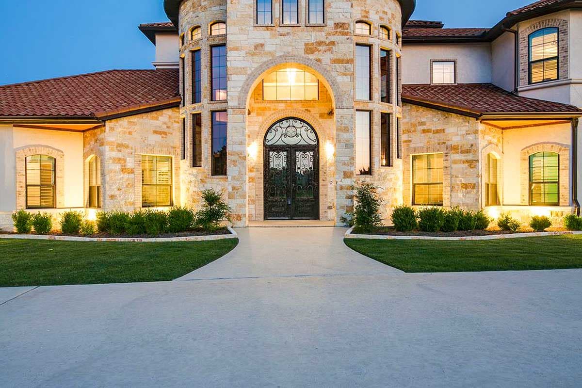 House plan exterior with stone facade, arched entryway, double doors, and multi-story turrets.
