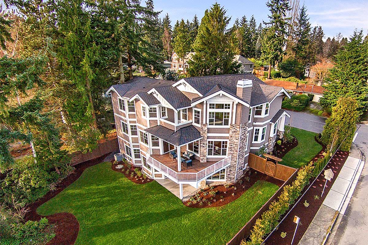 House plan exterior: Traditional style, three stories, multiple gables, stone-clad chimney, and a covered deck.