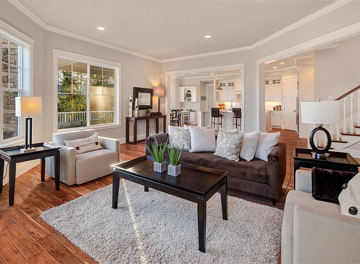 Interior view of living room with dark wood coffee table, sectional sofa, armchairs, and view into kitchen with island.