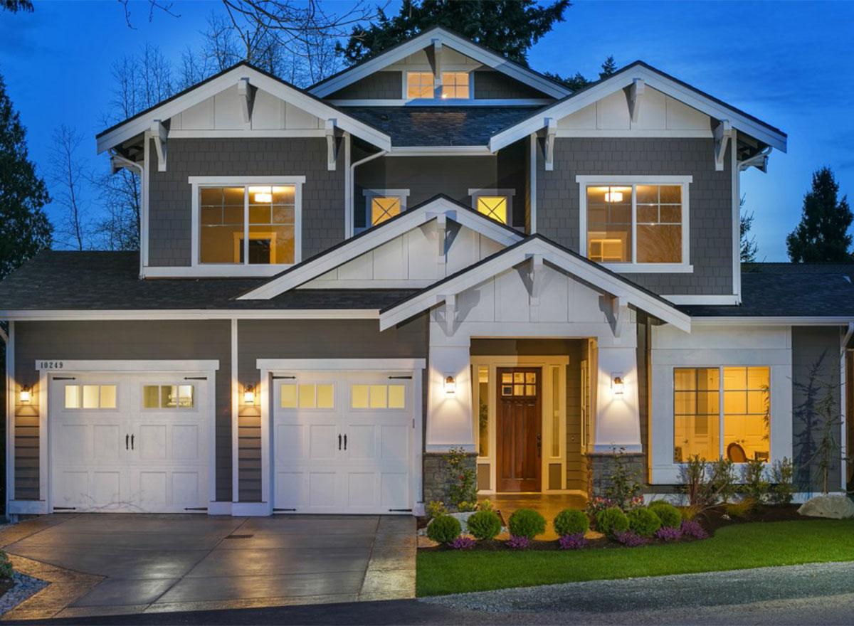 House plan exterior: Two-story modern farmhouse with a three-car garage, prominent gables, and a covered entry porch.