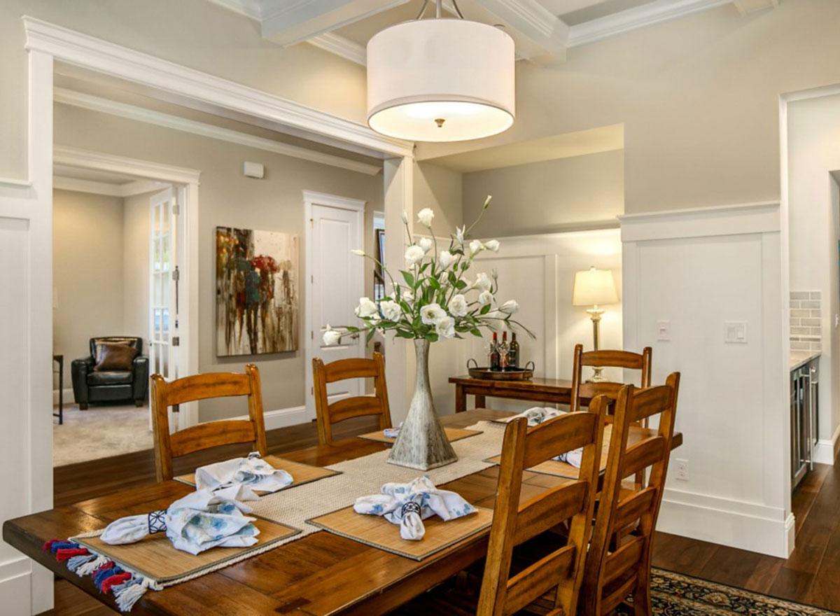 Dining room interior with wood table and chairs, decorative centerpiece, and view into a living room.