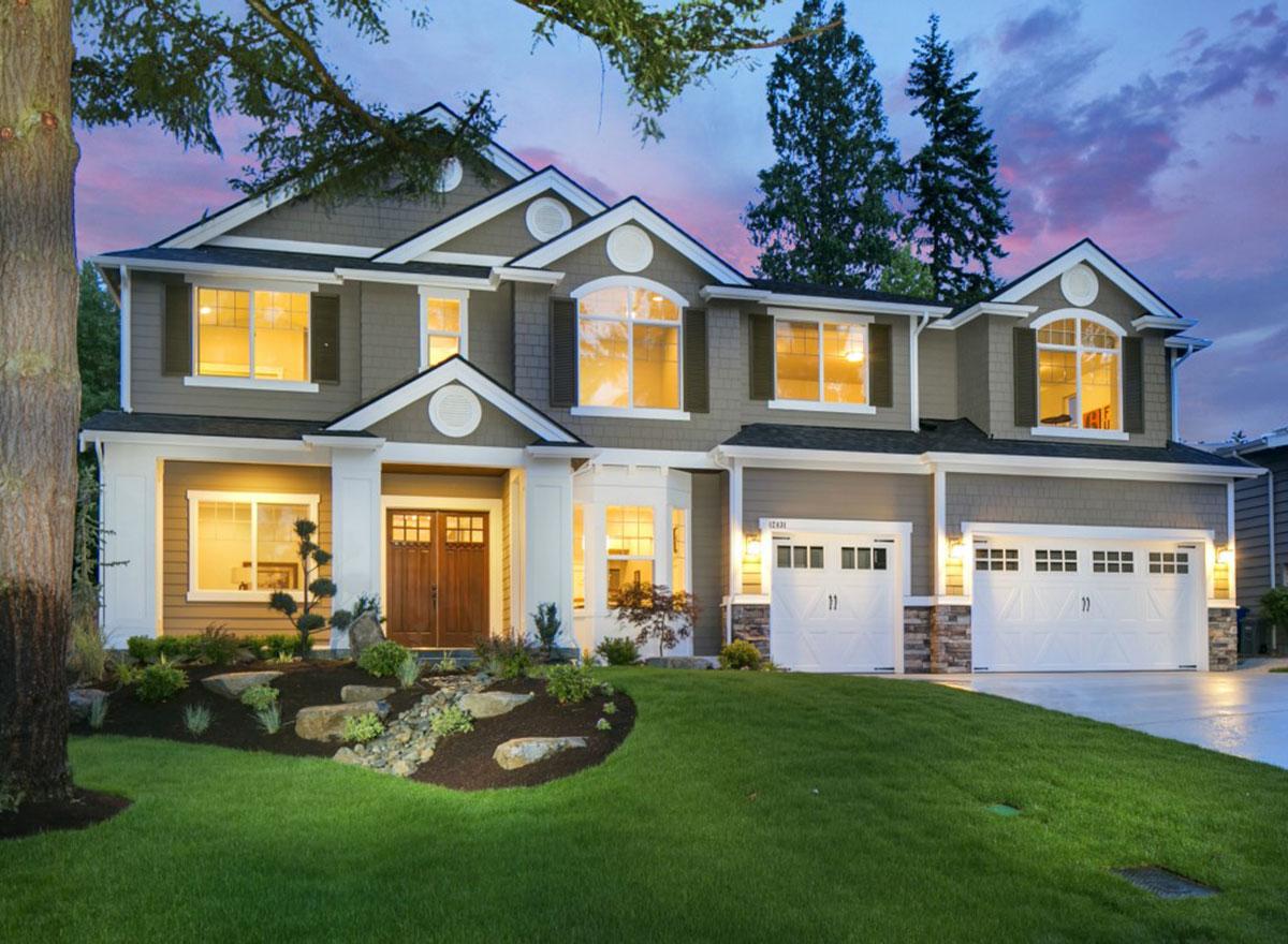 Two-story house plan exterior with a covered entry, arched dormers, stacked stone accents, and a three-car garage.