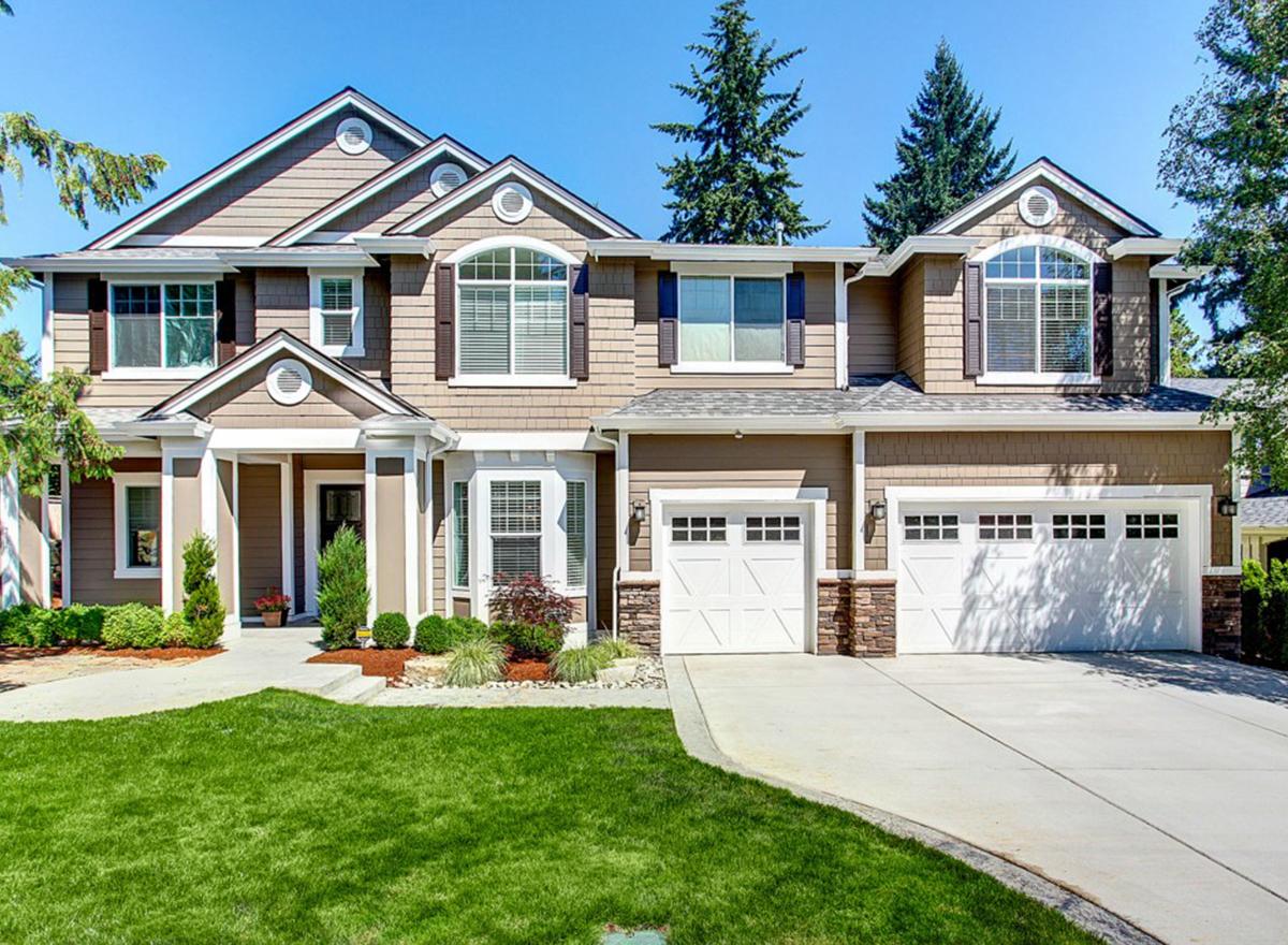 Two-story house plan exterior with brown siding, multiple gables, arched windows, and a three-car garage.