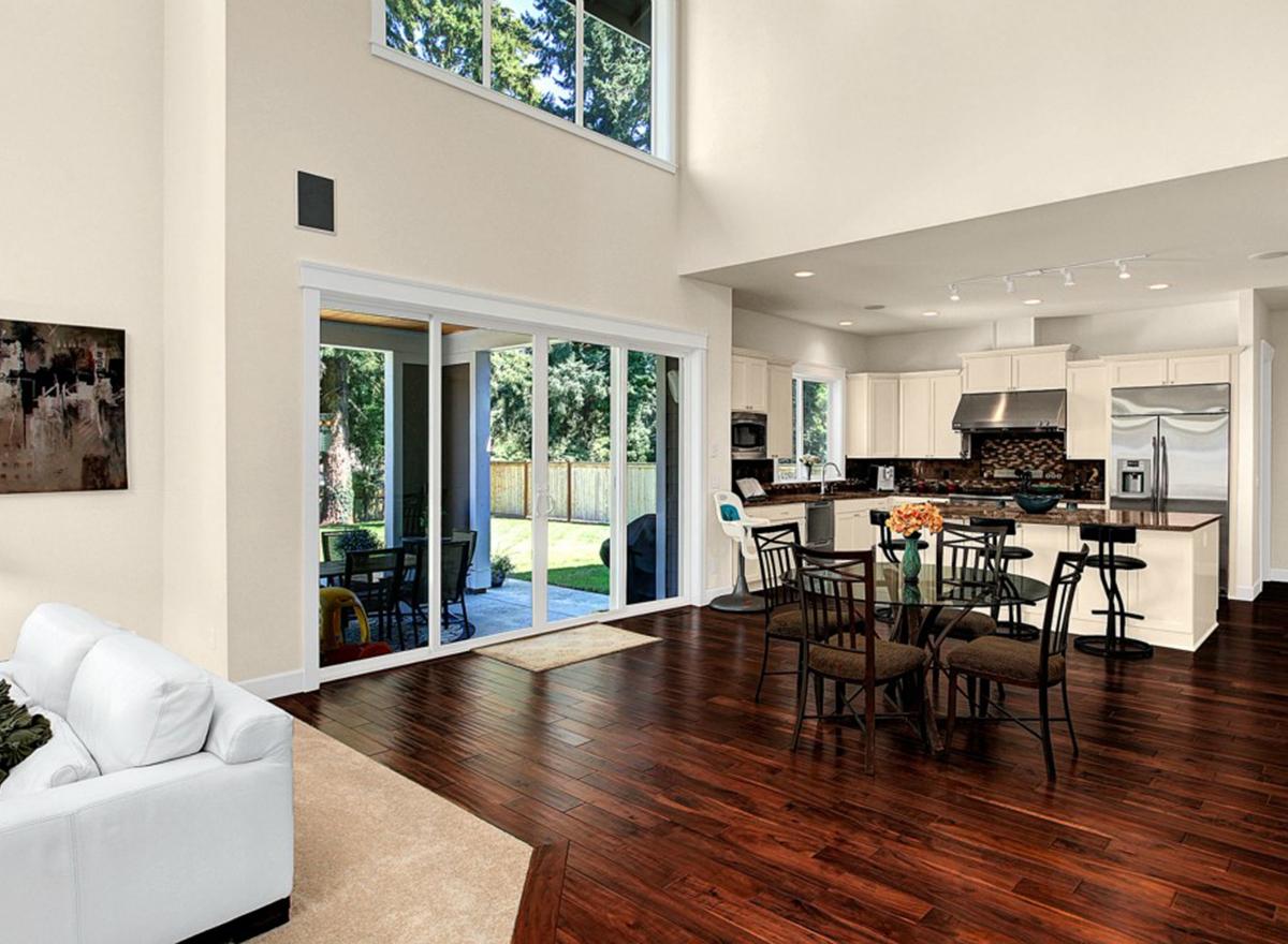Open concept living area with vaulted ceiling, sliding glass doors to backyard, and kitchen with island.