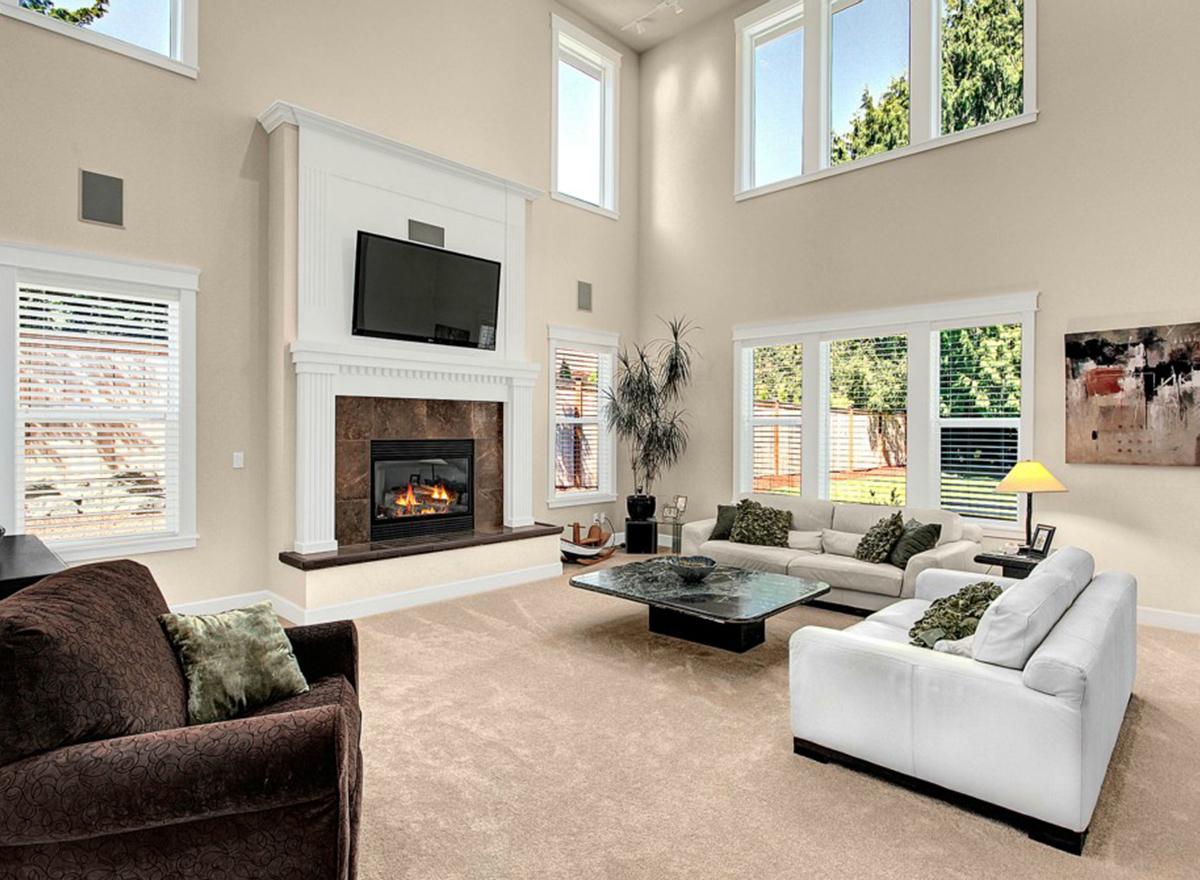 Great room interior with a floor-to-ceiling fireplace, vaulted ceiling, and large windows.