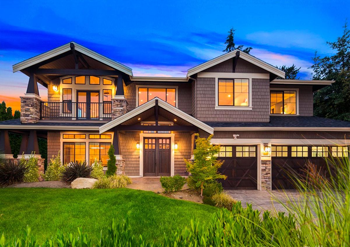 Two-story house plan exterior with wide gables, stone accents, upper balcony, and a three-car garage.