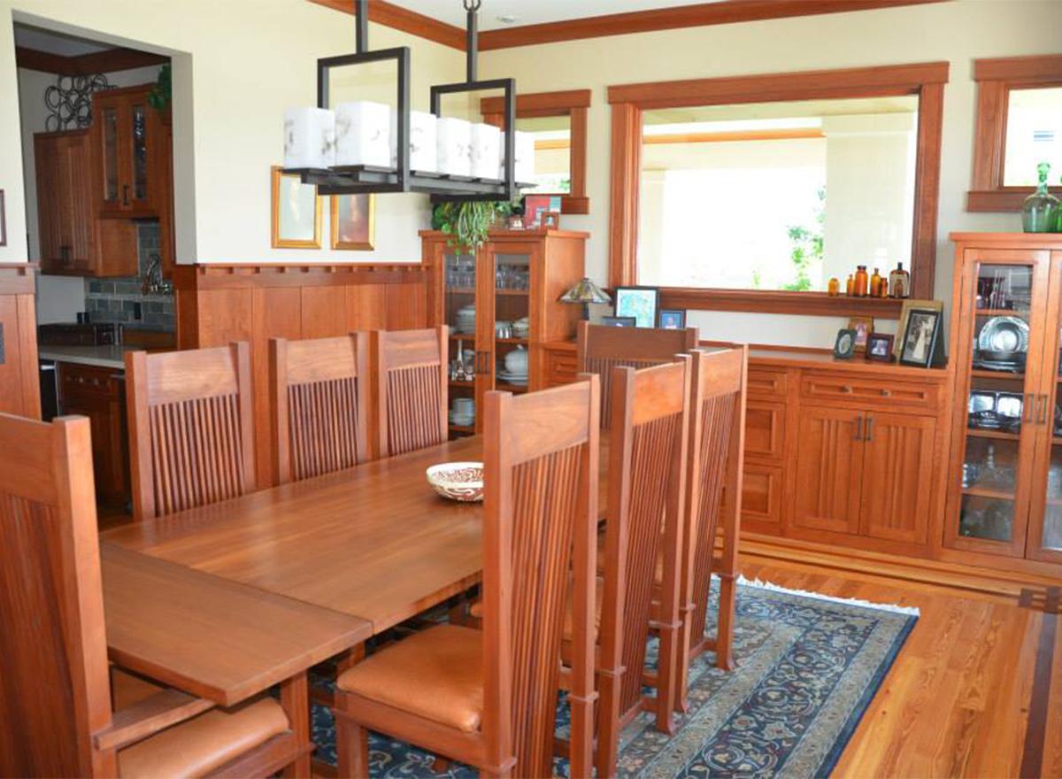 Dining room with a long wooden table, slatted chairs, built-in wood cabinetry, and a modern chandelier.