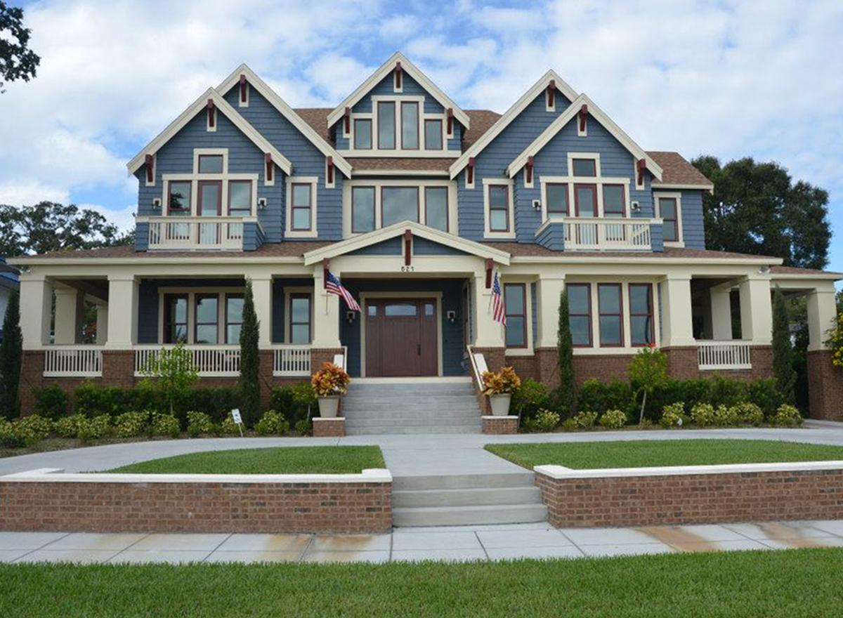 House plan exterior with full-width porch, multiple gables, dormers, and double-hung windows.