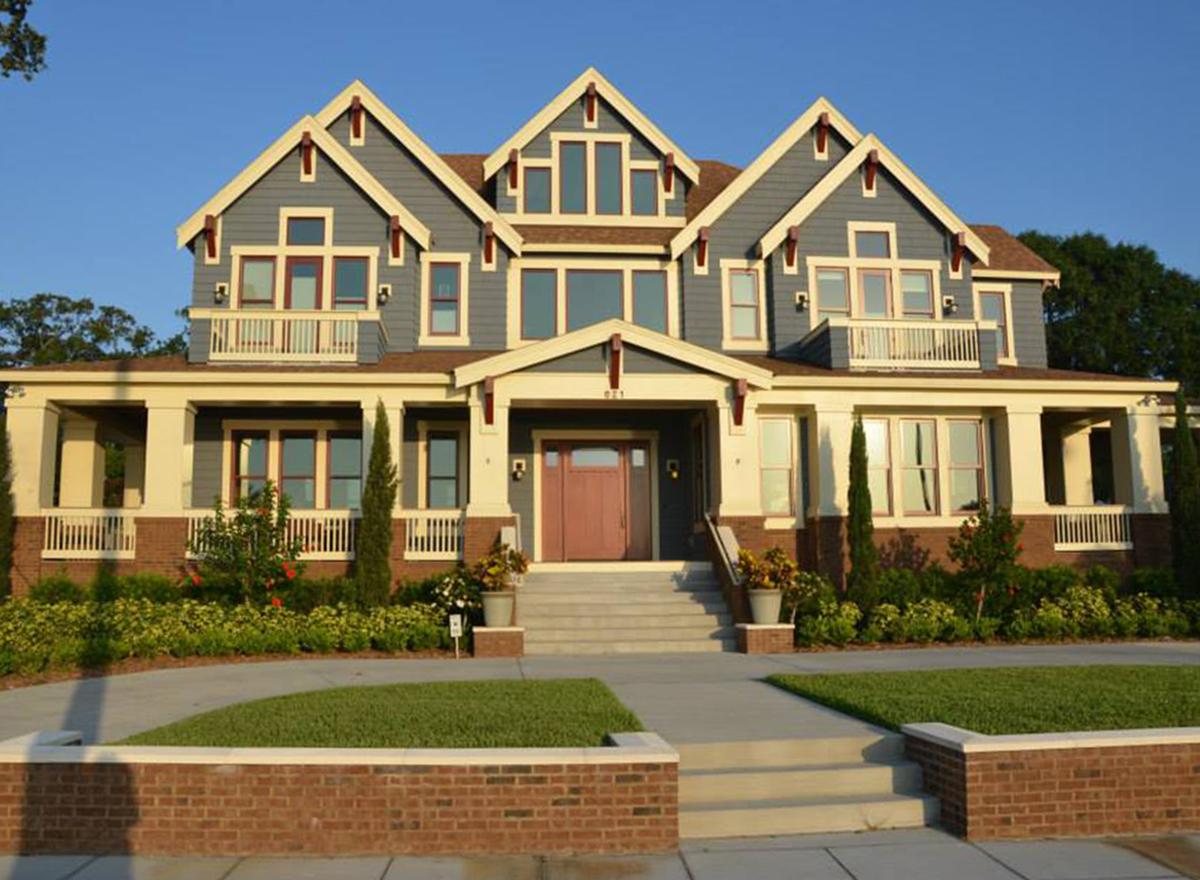 House plan exterior: Two-story home with wide wraparound porch, prominent gables, and dormer windows.