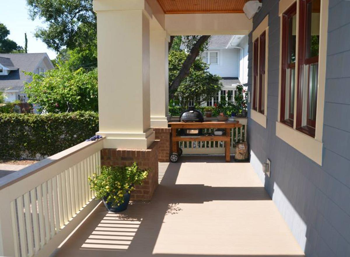 Porch exterior with squared columns, railings, and a table with a grill.
