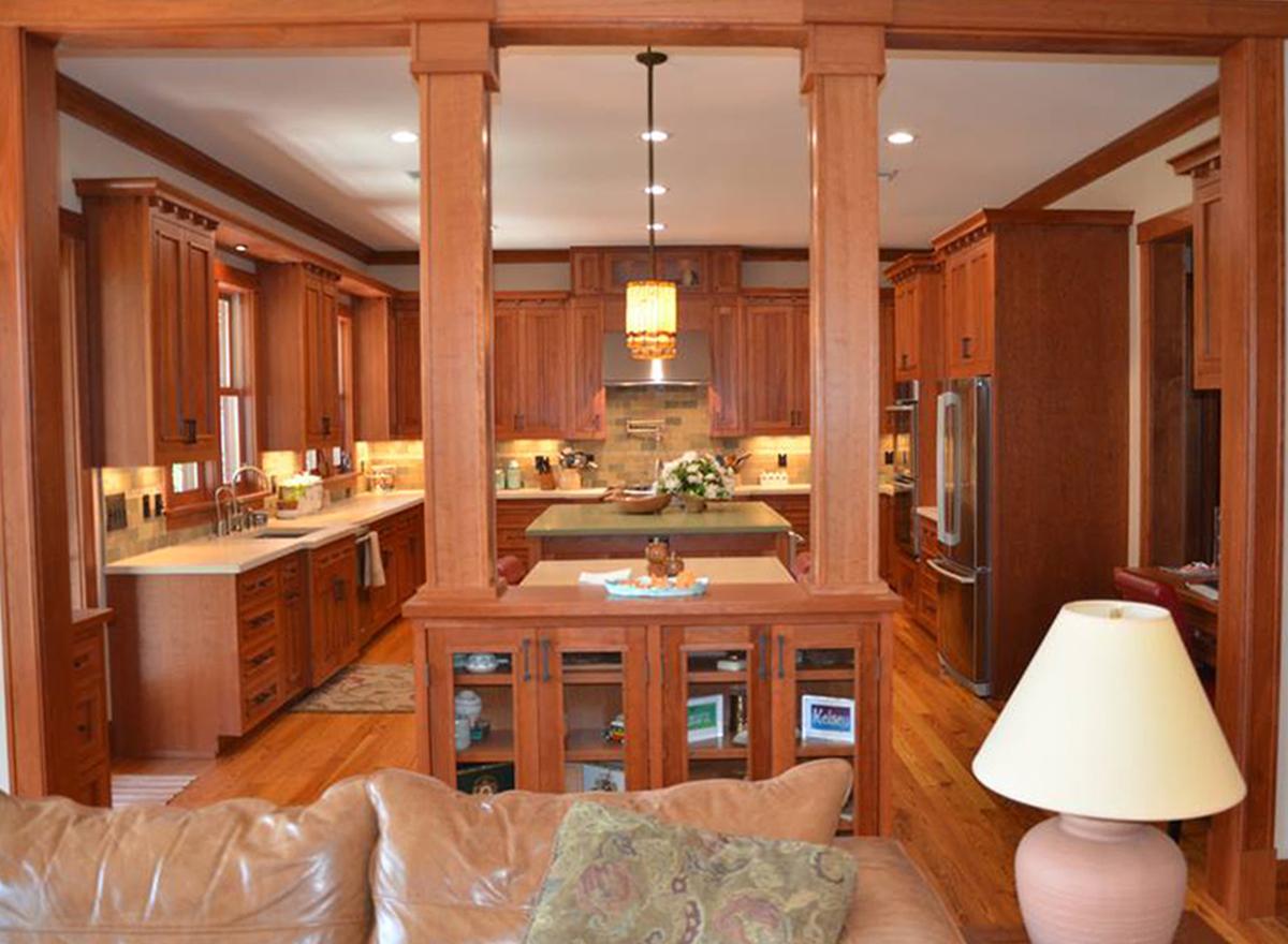 Kitchen with light wood cabinetry, center island with green countertop, and stainless steel appliances.