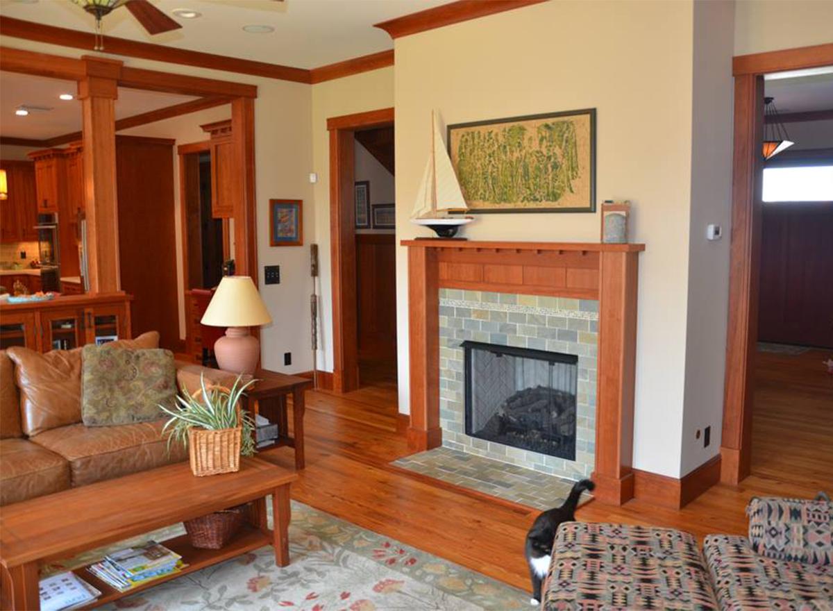 Living room with fireplace, wood trim, furniture, and access to kitchen and entryway.