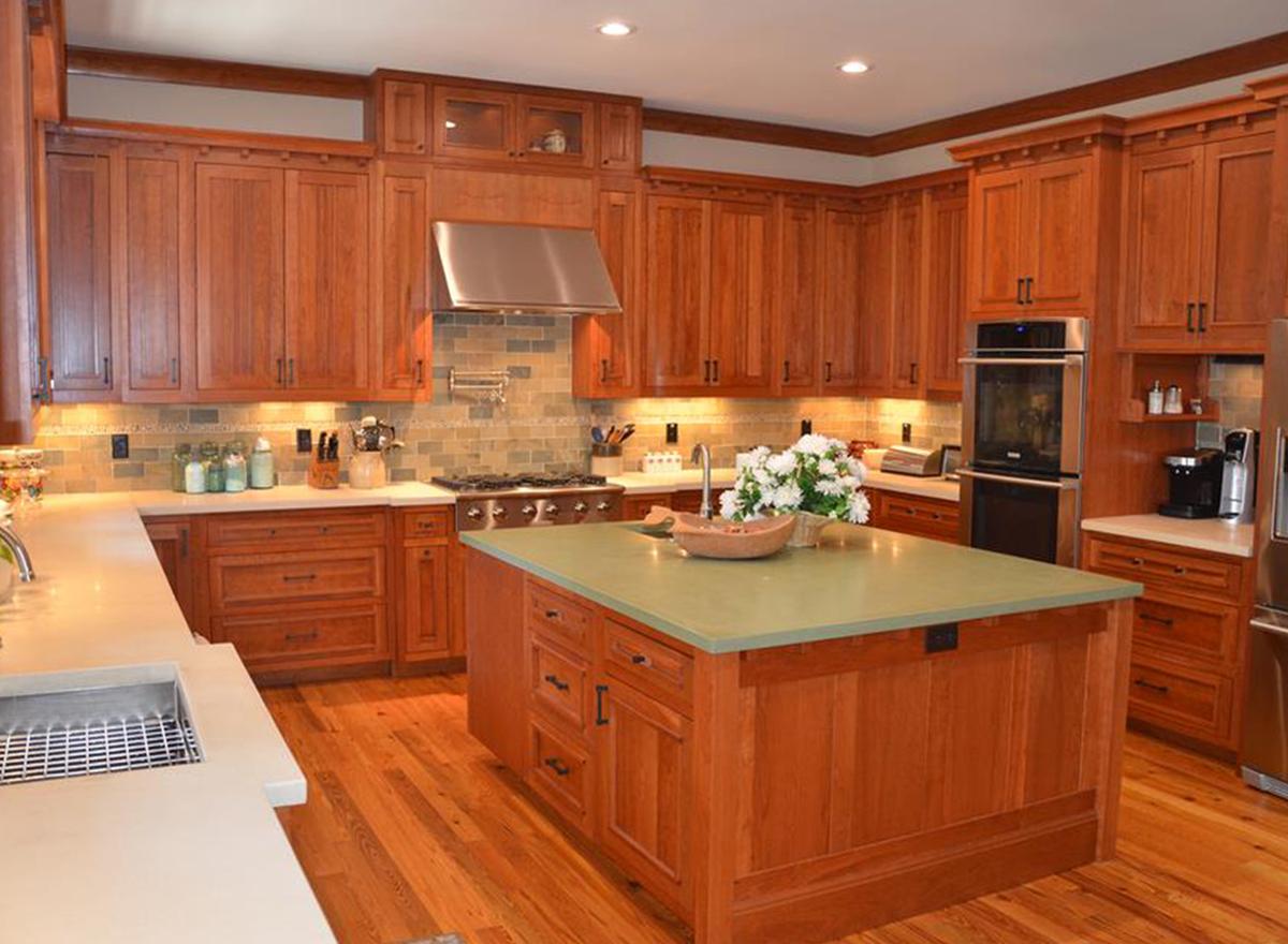 Kitchen interior with wood cabinetry, island with sink, gas range, and stainless steel appliances.