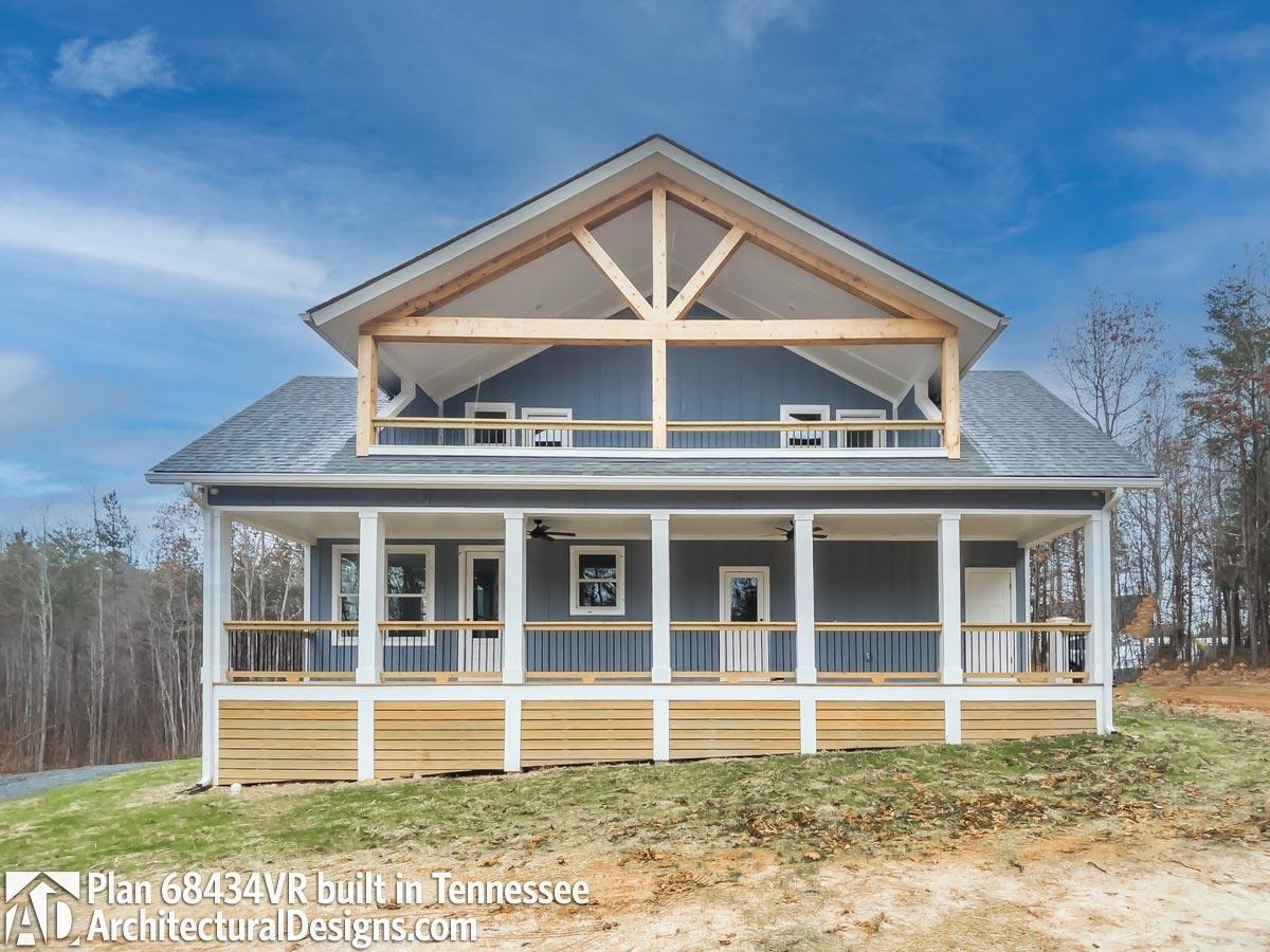 House plan exterior: two-story home with wraparound porch, exposed rafter tails, and a second-story balcony.