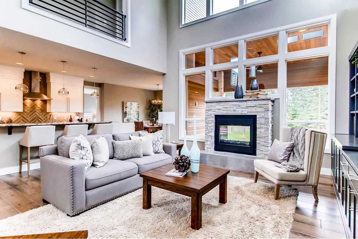 Great room with vaulted ceiling, stone fireplace, island kitchen, and large windows.