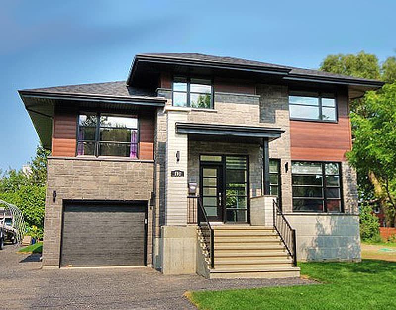 Two-story modern house plan exterior with stone and wood siding, a covered entryway, and a side-facing garage.