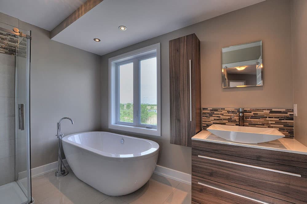 Modern bathroom with freestanding tub, glass shower enclosure, floating vanity with vessel sink, and a large window.