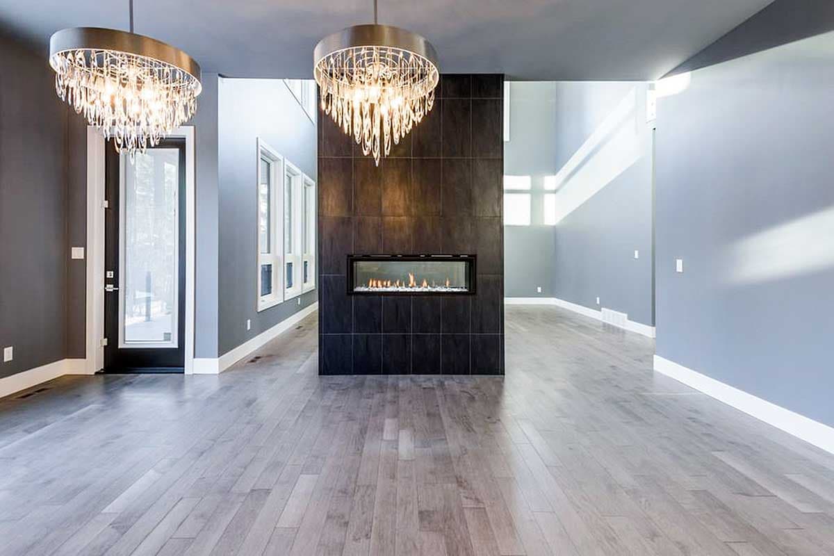 Contemporary living room with linear gas fireplace, large windows, and two modern chandeliers.