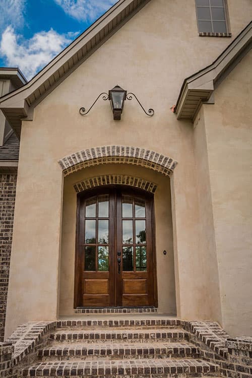 House plan exterior with arched double doors, brick steps, arched brick entryway, and decorative lantern.