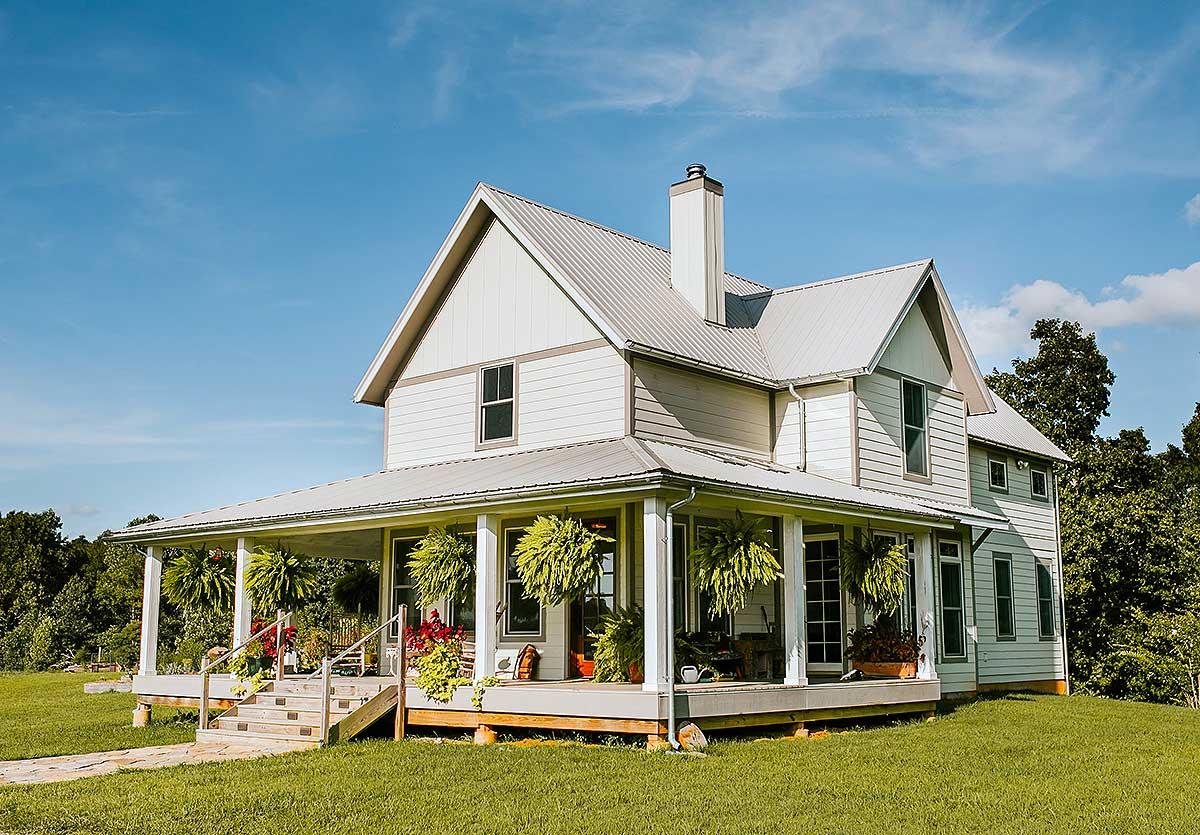 Two-story Modern Farmhouse exterior with a wrap-around porch, gabled dormers, and a standing seam metal roof.