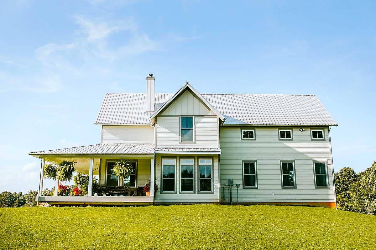 Modern Farmhouse style house plan exterior with a wrap-around porch, metal roof, gabled dormers, and multiple stories.