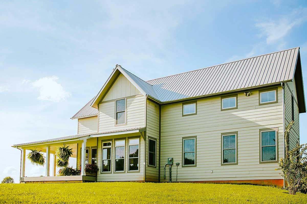 Two-story Modern Farmhouse exterior with a wraparound porch, gables, and metal roof.