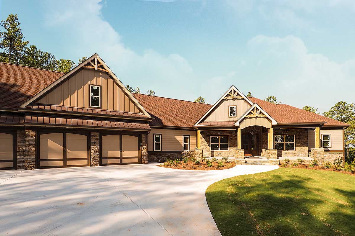 House plan exterior: Craftsman-style home with three-car garage, stone accents, prominent gables, and covered entry.