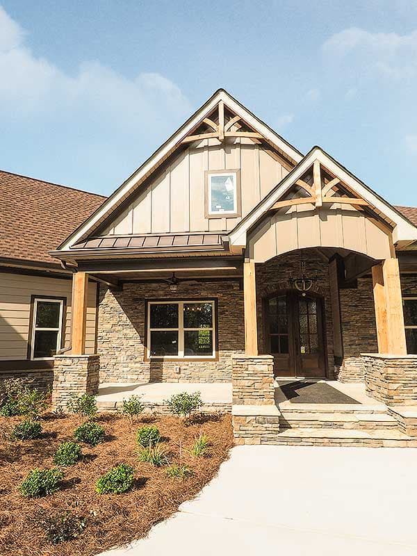 House plan exterior: Craftsman style with stone accents, exposed beams in gables, and covered entry porch.