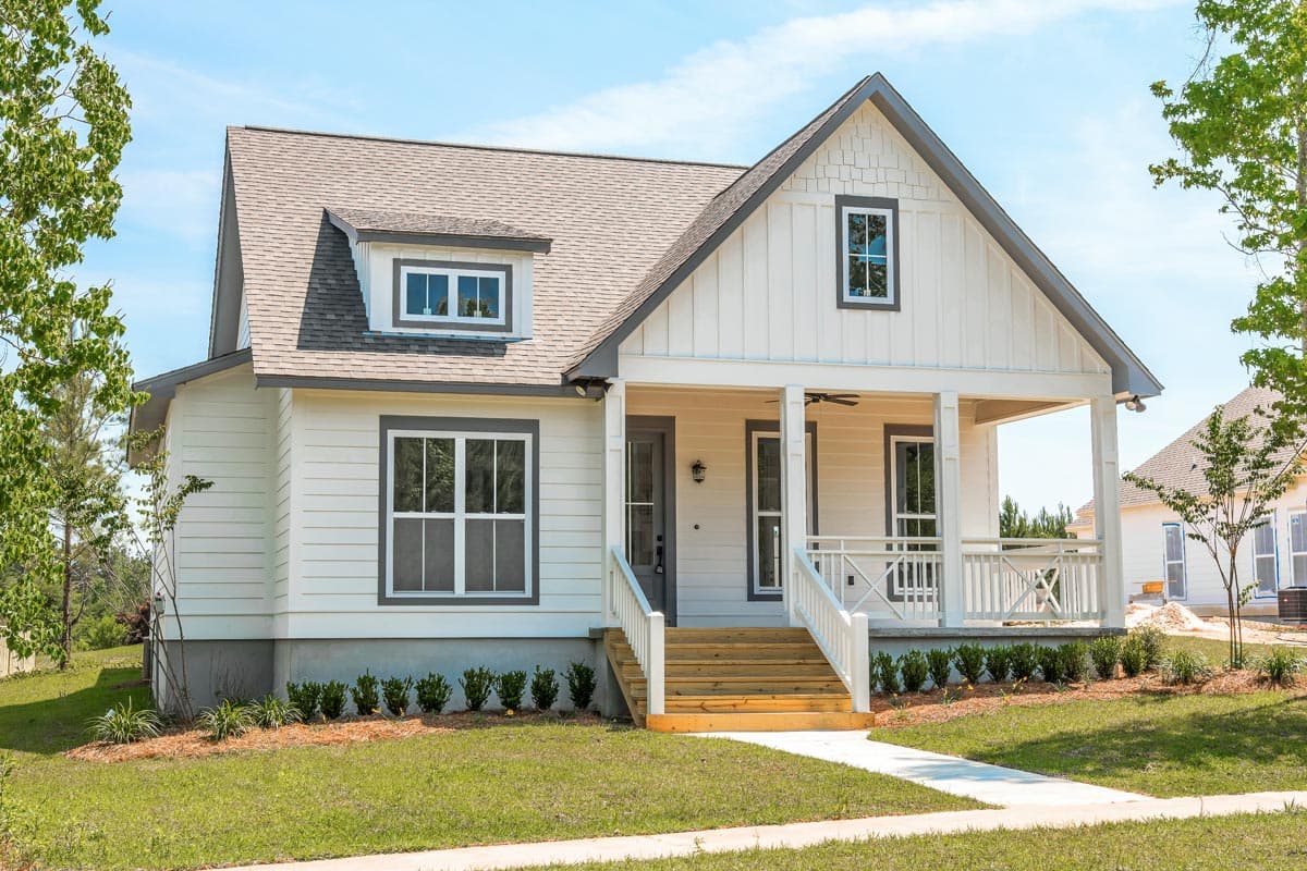 House plan exterior: Modern Farmhouse style, one-and-a-half stories, featuring a gabled front, dormer, and covered front porch with railings.