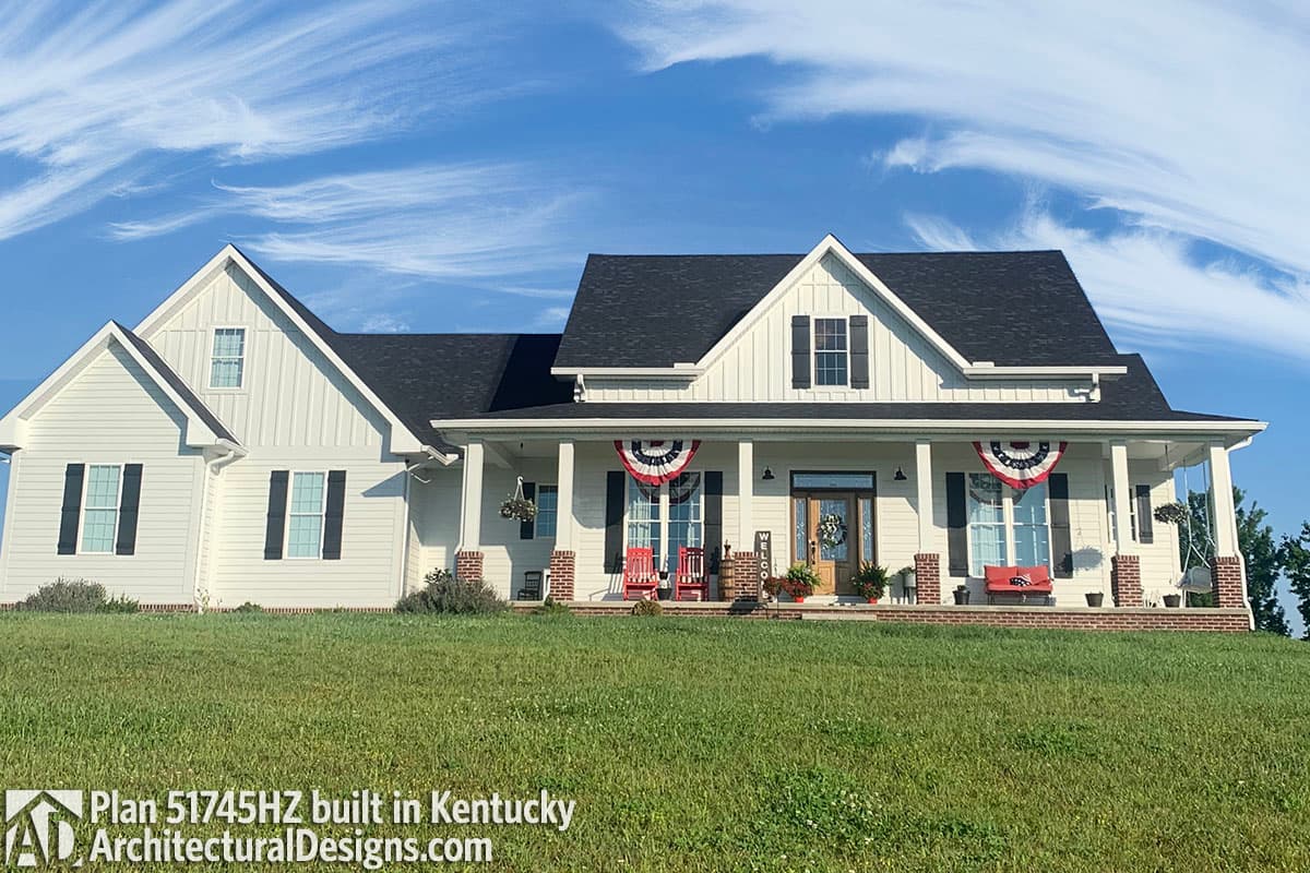 Modern farmhouse style house plan exterior with wide covered front porch, gables, dormers, and vertical siding.
