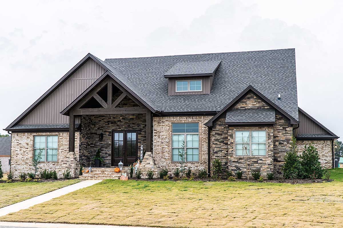 House plan exterior: Ranch style with prominent gables, stone veneer, covered porch with exposed beams, and dormer.
