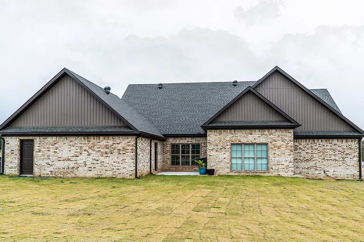 House plan exterior: Brick, one-story home with multiple gables, dark roof, and vertical siding accents.