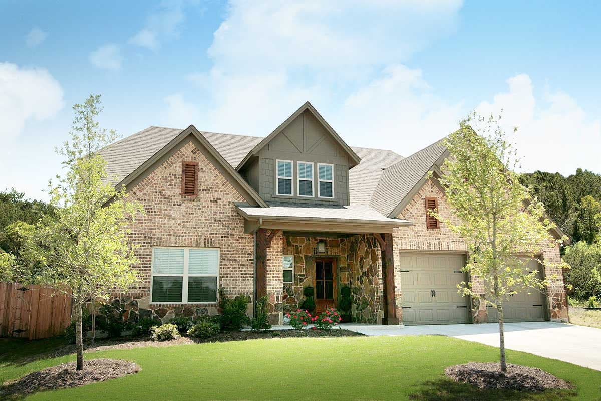 House plan exterior with Craftsman style. Features include a stone-covered porch, gables, brick facade, and an attached two-car garage.