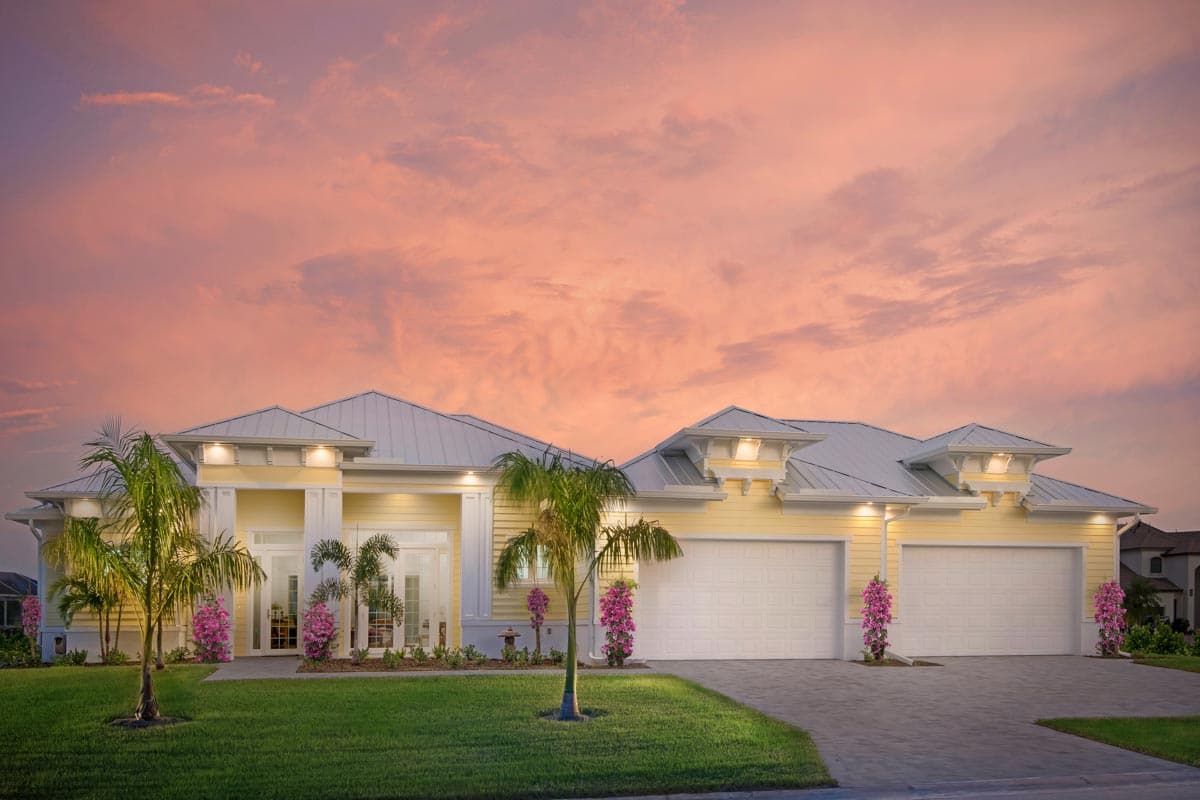 House plan exterior: single-story home with metal roof, four-car garage, and covered entry with columns.