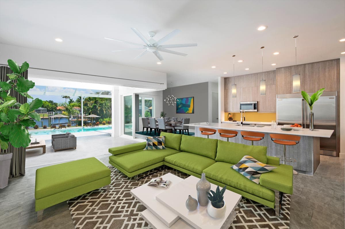 Modern open-concept living area with island kitchen, dining space, and sliding doors to pool area.