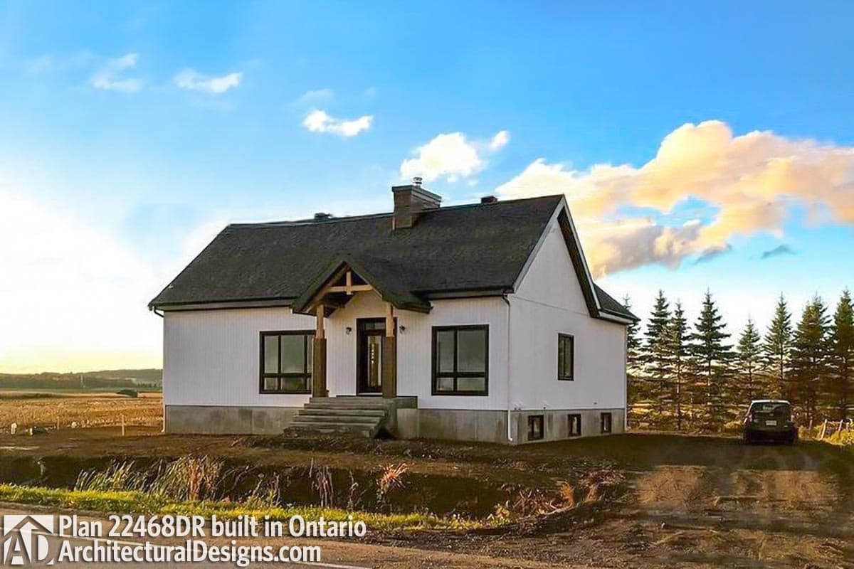 House plan exterior with modern farmhouse style, gabled roof, covered entry with wooden posts, and large windows.